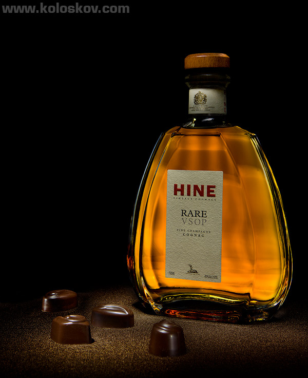 rare hine cognac squared bottle chocolates sitting in gold dust on black background